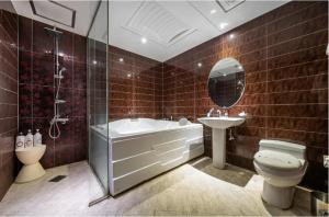 a bathroom with a tub and a toilet and a sink at 프롬에이치 아모레미오 더클래식 수원역 in Suwon