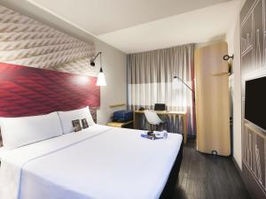 a hotel room with a large white bed and a desk at ibis Navegantes Itajai in Itajaí