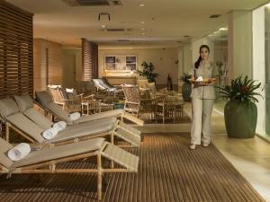 una mujer parada en un vestíbulo con un plato de comida en Hotel Jequitimar Guaruja Resort & Spa by Accor - Ex Sofitel, en Guarujá 148 fotos más