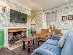 a living room with a blue couch and a fireplace at Mercure Salisbury White Hart Hotel & Apartments in Salisbury