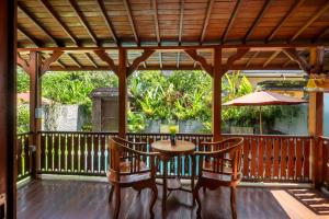 a porch with a table and chairs and an umbrella at Anggi Villas Ubud in Tegalalang
