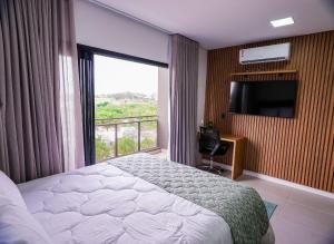 una camera da letto con un letto e una finestra con una televisione di Moov Smart Home – Studios e Apartamentos por Temporada em Cuiabá a Cuiabá Altre 205 foto