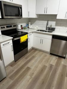 a kitchen with black and white appliances and wooden floors at Bedroom in the basement Upland 2 in Edmonton