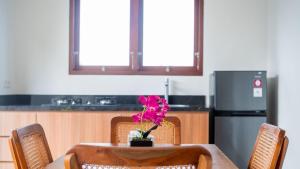 una mesa con una flor rosa encima en Adhy Villa Ubud by Bali Cabin, en Ubud