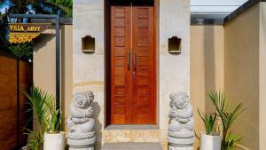 Una puerta de madera con dos estatuas frente a una casa. en Adhy Villa Ubud by Bali Cabin, en Ubud 13 fotos más