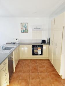 une cuisine avec un évier et une cuisinière dans l'établissement Scenic Coastal Gem with Pool, Tennis, Securely Gated, à Whangaparaoa 7 autres photos