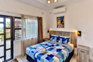 a bedroom with a bed with blue and white sheets at Rembrandt in Ballito