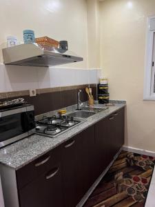 a kitchen with a stove and a sink and a microwave at Résidences tazerzit smouna in Agadir