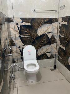 Un baño con inodoro con un mural de hojas. en Gavi Paradise Homestay, en Vandanmedu