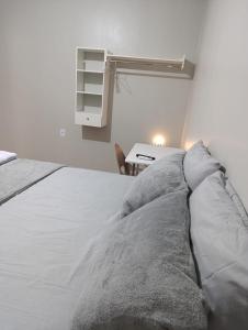 Un dormitorio con una cama blanca y un escritorio. en Pousada Luz do Norte - Centro de Macapá, en Macapá