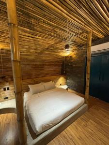 a bed in a room with a wooden ceiling at Kenanga Bamboo Villa in Dinalupihan