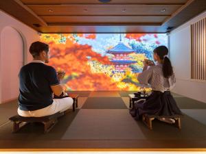 un homme et une femme assis devant un tableau dans l'établissement HANARE by Tokyu Stay Kyoto Sanjo, à Kyoto