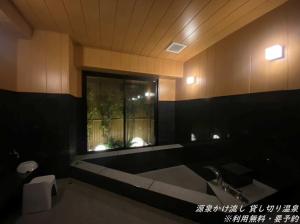 a bathroom with a tub and a sink and a window at BEPPU Sento in Beppu
