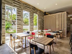 a restaurant with wooden tables and chairs and windows at Ibis Merida in Mérida +46 photos
