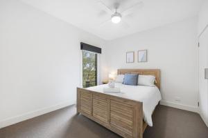 a white bedroom with a bed and a window at Nautilus Rise – Panoramic Bay Coastal Views in Tootgarook