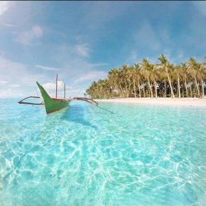a boat sitting in the water near a beach at Aulea Siargao in General Luna