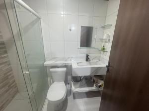 a white bathroom with a toilet and a sink at kitnet in Colombo