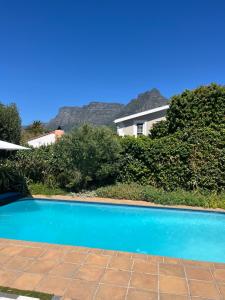 a blue swimming pool in front of a house at The Pillans Manor Studio in Cape Town