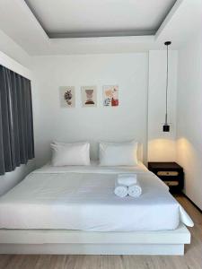 a bedroom with a white bed with two towels on it at Jellyfish Residence Patong in Patong Beach