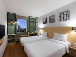 a hotel room with two beds and a tv at Ibis Bangkok Sukhumvit 4 in Bangkok +51 photos