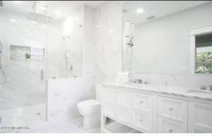 a white bathroom with a shower and a toilet at 4 bedroom home- historic-downtown jax- min to UF health and everbank stadium in Jacksonville