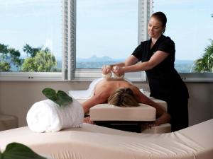 a womanties a mans head in a massage room at Mercure Clear Mountain Lodge in Mount Samson