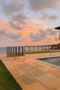 a view of the beach at sunset with a pier at Apartamento no Falésias de Pipa - Veleiros 212 in Pipa
