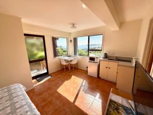 a room with a kitchen with a table and some windows at The Tuibird Room in Russell