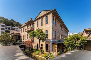 an old brick building with trees in front of it at The Woven Inn in Shunde