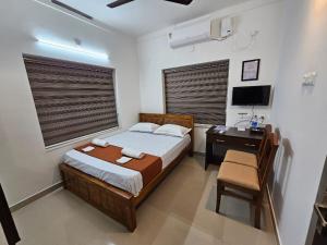 a bedroom with a bed and a desk with a computer at Guruvayur Nest Homestay in Guruvāyūr