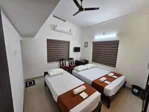 a bedroom with two beds and a ceiling fan at Guruvayur Nest Homestay in Guruvāyūr +13 photos