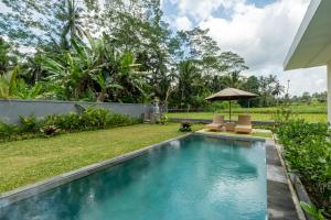 a swimming pool with two chairs and an umbrella at Sinden Villa in Payangan