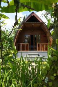 a small wooden cabin with a porch in a forest at Made Misi Homestay & Guesthouse in Penginyahan