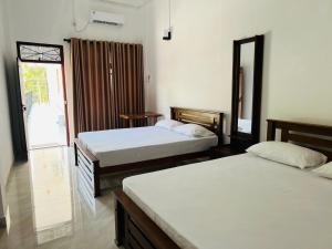 a bedroom with two beds and a window at Nishadi Holiday Inn Kataragama in Kataragama