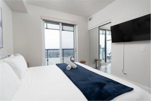 - une chambre avec un lit blanc, une télévision et des fenêtres dans l'établissement 3BR Skyline Condo - By CN Tower & MTCC & Free Parking, à Toronto