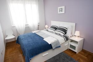 a white bedroom with a large bed with blue blanket at Paw Rooms in Zagreb