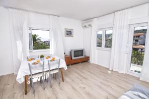a white dining room with a table and a tv at Apartament Skoko in Slatine