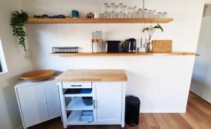 a kitchen with a white counter with a wooden counter top at Wurtulla Guesthouse, Modern & Tranquil in Kawana Waters