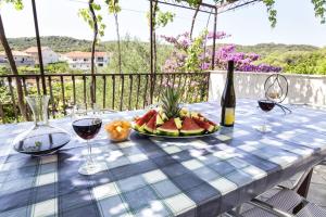 a table with a plate of fruit and wine glasses at Apartament Skoko in Slatine