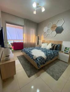 a bedroom with a bed and a desk and a television at Beach Appartement & Résidence Luxury Aourir in Agadir