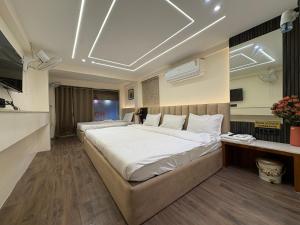 Un dormitorio con una cama grande con sábanas blancas. en Hotel Anantshree, en Ujjain