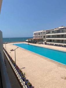 a large swimming pool next to a building and the ocean at Beach Appartement & Résidence Luxury Aourir in Agadir