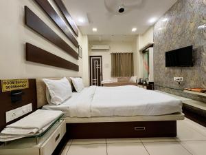Un dormitorio con una cama grande y un televisor. en Hotel Anantshree, en Ujjain