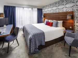 a hotel room with a bed and two chairs and a desk at Mercure Brighton Seafront Hotel in Brighton & Hove +125 photos