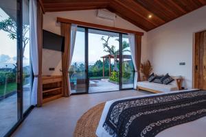 a bedroom with a large bed and a large window at KAPI Sebatu Villa in Tampaksiring +48 photos