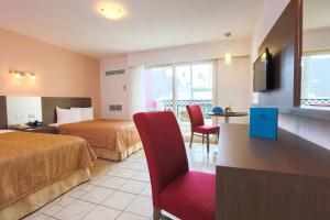 プエルト・バジャルタにあるCrown Paradise Club All Inclusiveのベッド2台と赤い椅子が備わるホテルルームです。