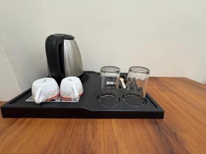 a tray with a coffee maker and glasses on a table at Hotel Anantshree Inn Shree Mahakaleshwar Temple Ujjain in Ujjain +61 photos
