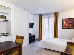 a hotel room with a bed and a table and a desk at Aparthotel Adagio Access Nice Garibaldi in Nice