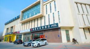 a building with two cars parked in front of it at Thank Inn Hotel Tianjing Jinnan University in Tianjin
