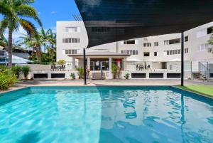 a swimming pool in front of a building at Azure at The Edge, Steps to the Esplanade in Cairns North